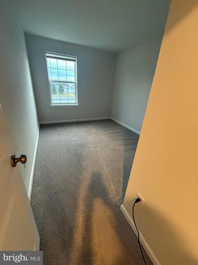 carpeted spare room featuring baseboards