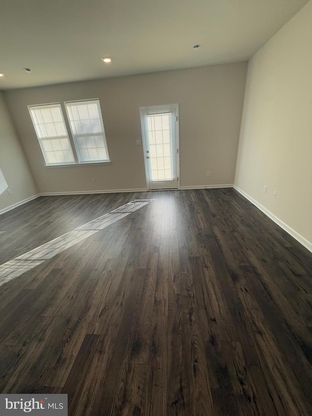 spare room featuring baseboards, dark wood-type flooring, and recessed lighting