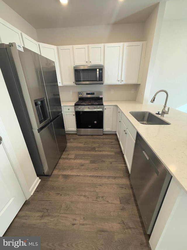 kitchen with stainless steel appliances, dark wood finished floors, white cabinetry, and a sink