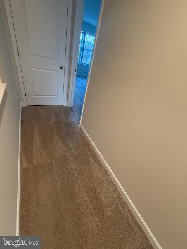 hallway featuring carpet floors and baseboards