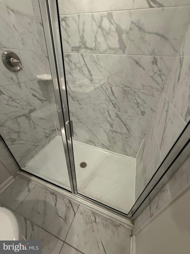 full bath featuring marble finish floor and a shower stall