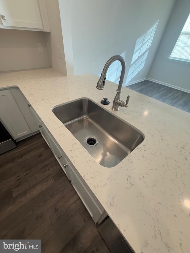 details with white cabinets, light stone countertops, dark wood-type flooring, and a sink