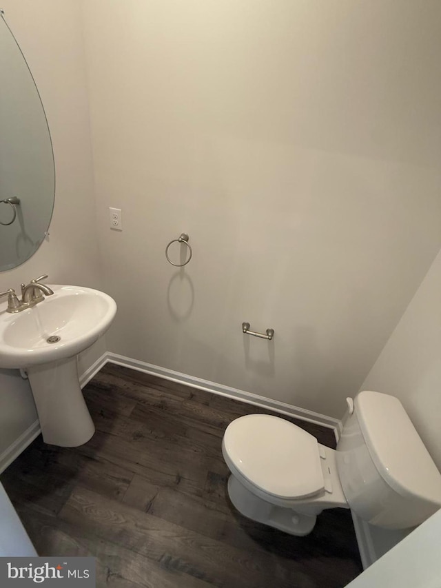 half bathroom featuring baseboards, toilet, and wood finished floors