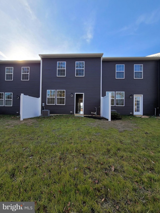 rear view of house featuring a lawn and central AC unit