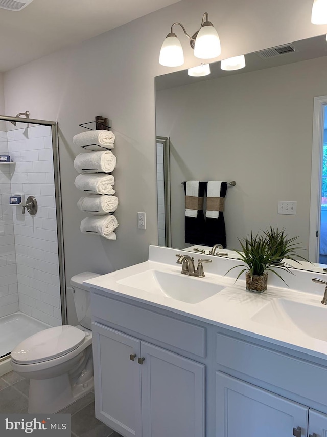 bathroom with a sink, a shower stall, toilet, and double vanity