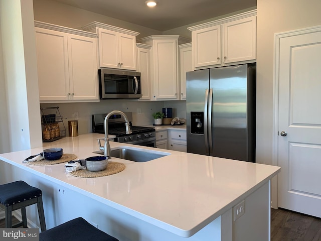 kitchen with a peninsula, a breakfast bar, white cabinets, and stainless steel appliances