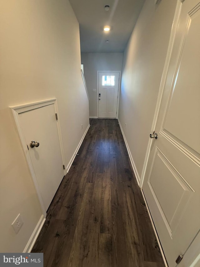 hall with dark wood-type flooring and baseboards