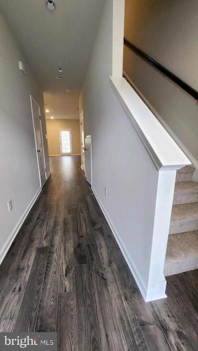 hallway with stairs, dark wood finished floors, and baseboards