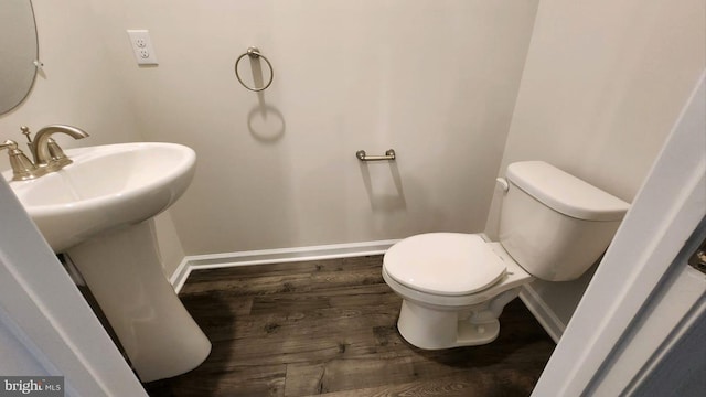 half bathroom with a sink, wood finished floors, toilet, and baseboards