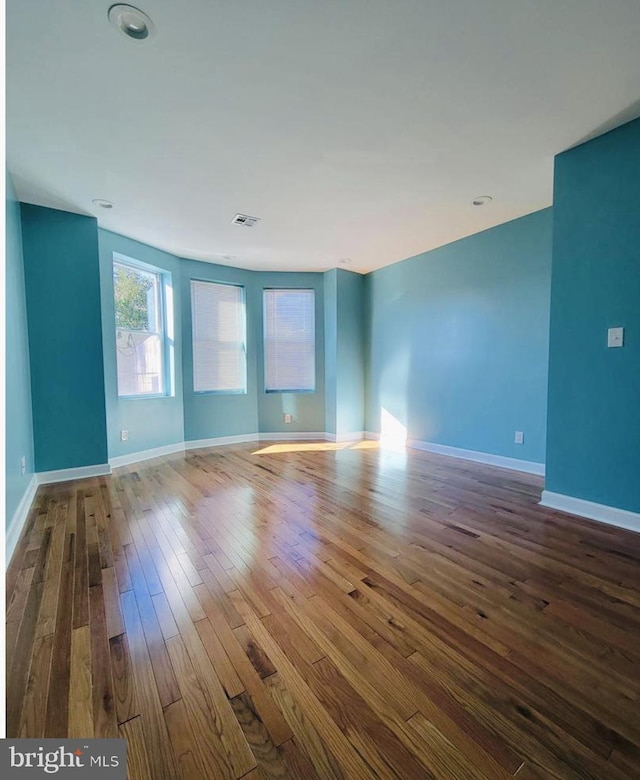 unfurnished room with dark wood-style floors, baseboards, and visible vents