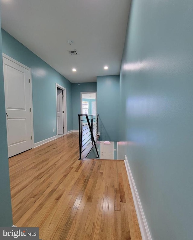 hallway with recessed lighting, visible vents, an upstairs landing, baseboards, and hardwood / wood-style flooring