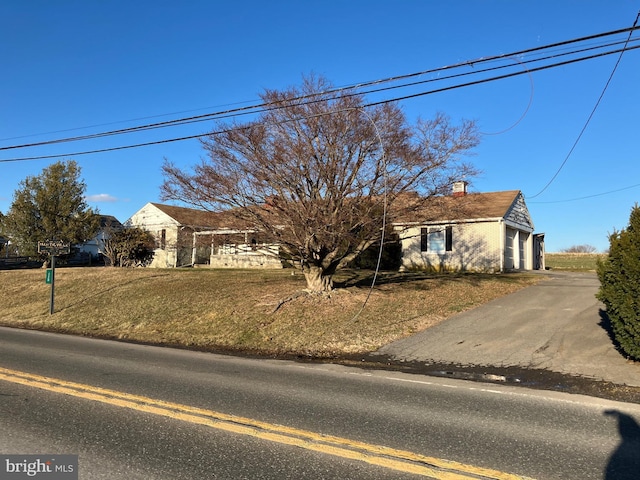 ranch-style house with a front yard, driveway, and a chimney