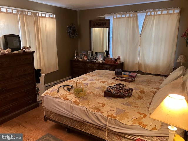 bedroom with a baseboard radiator and wood finished floors