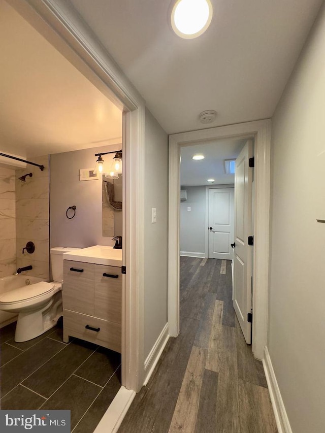 hall featuring dark wood-style flooring, visible vents, a sink, and baseboards