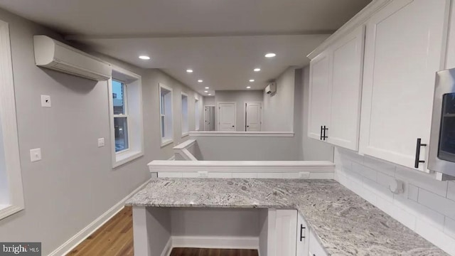 bathroom featuring a wall unit AC, recessed lighting, wood finished floors, baseboards, and decorative backsplash