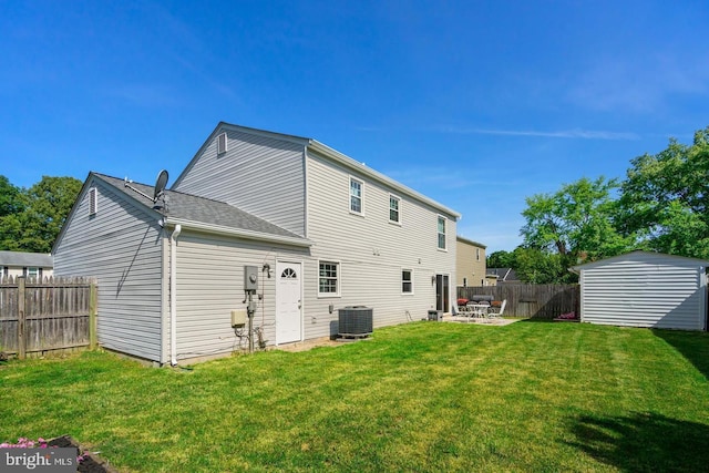 back of house featuring a lawn, a patio, fence, an outdoor structure, and central AC