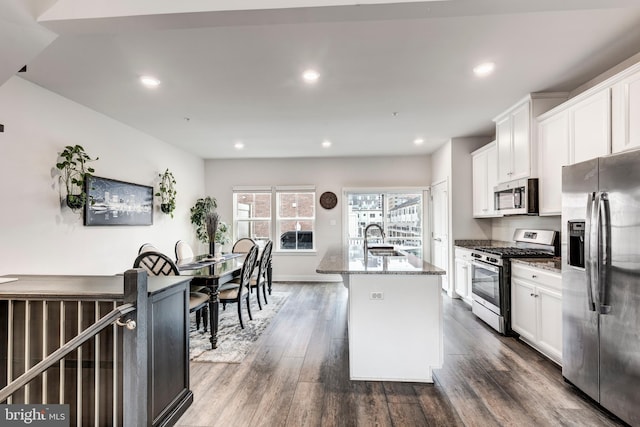 kitchen with stone counters, stainless steel appliances, dark wood-type flooring, a sink, and white cabinetry