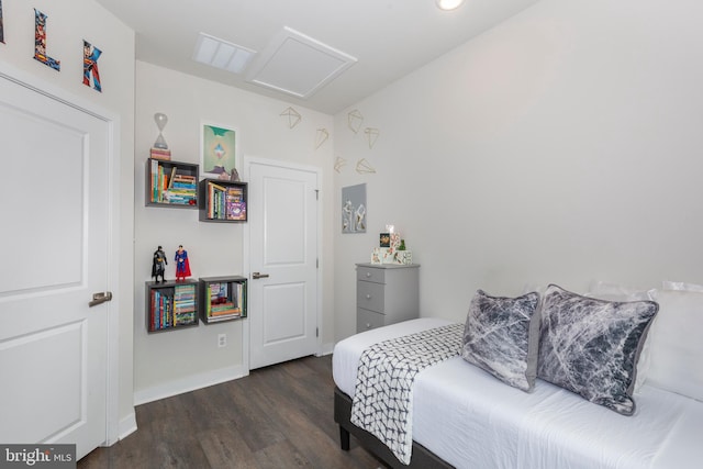 bedroom with attic access, baseboards, and wood finished floors