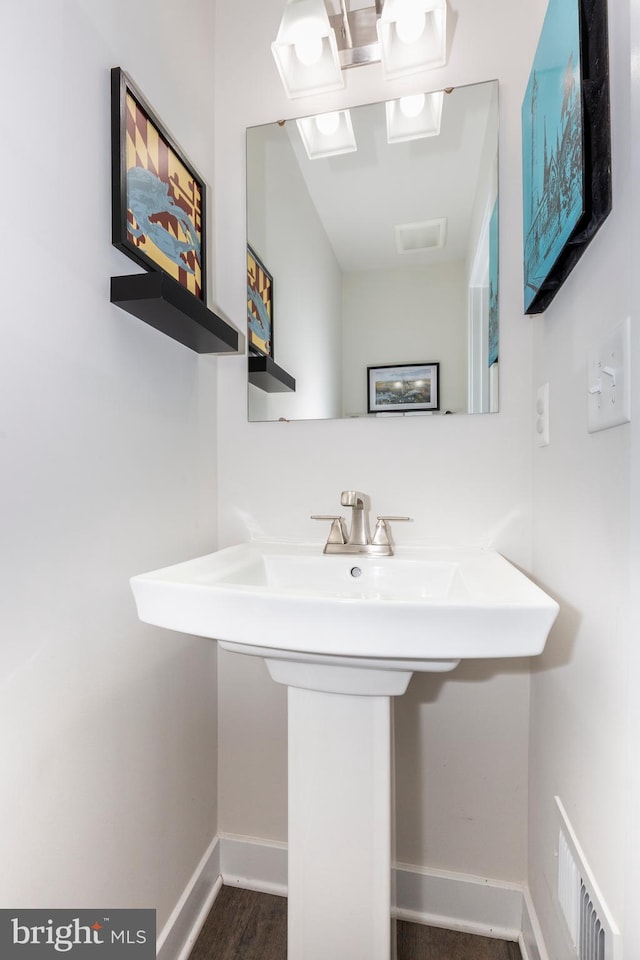 bathroom featuring visible vents, a sink, baseboards, and wood finished floors