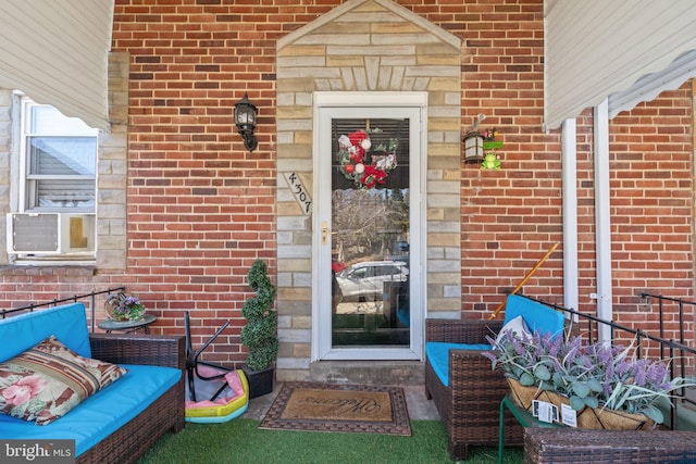 view of exterior entry with cooling unit and brick siding