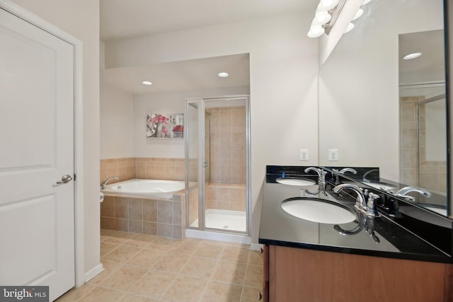 full bath featuring a bath, a stall shower, tile patterned flooring, and a sink