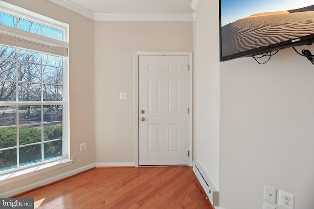 foyer entrance with a healthy amount of sunlight, a baseboard radiator, crown molding, and wood finished floors