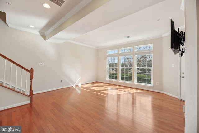 unfurnished living room with baseboards, visible vents, stairway, ornamental molding, and hardwood / wood-style floors