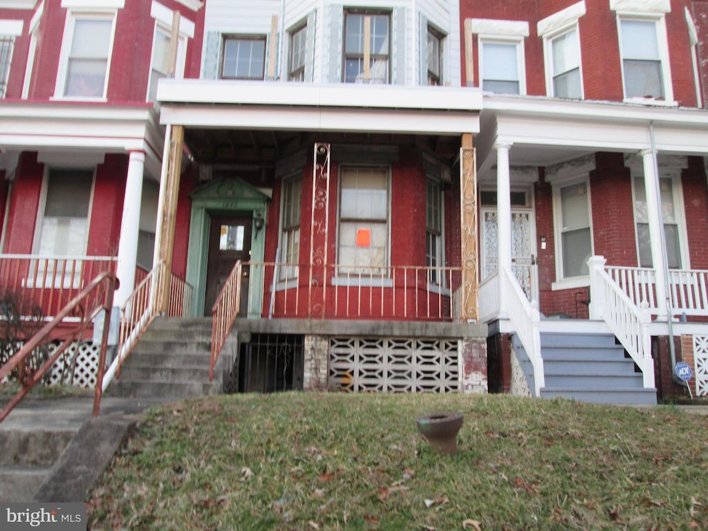 entrance to property featuring a porch and brick siding