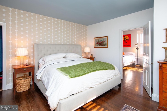 bedroom with an accent wall, wood finished floors, baseboards, and wallpapered walls