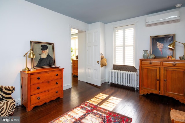 sitting room with plenty of natural light, dark wood-style flooring, radiator heating unit, and a wall unit AC