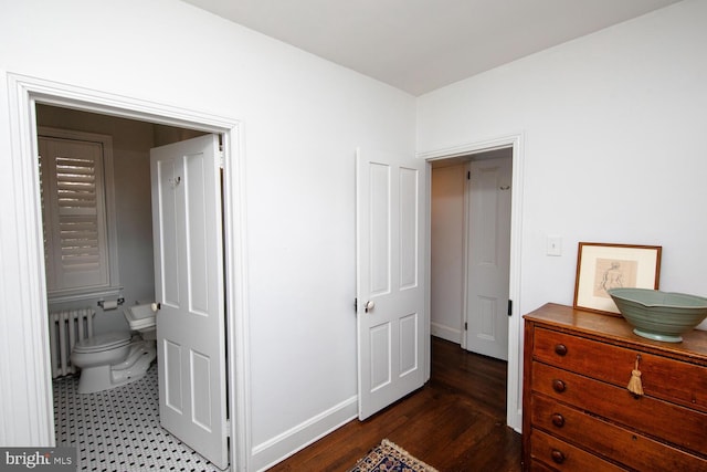 interior space with ensuite bath, radiator heating unit, baseboards, and wood finished floors