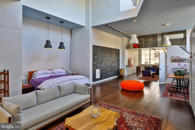 living room featuring baseboards, a high ceiling, hardwood / wood-style flooring, and radiator