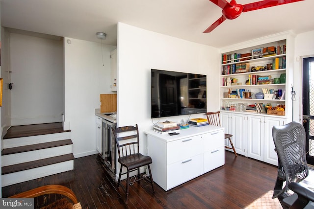 office space with built in features, dark wood finished floors, and ceiling fan