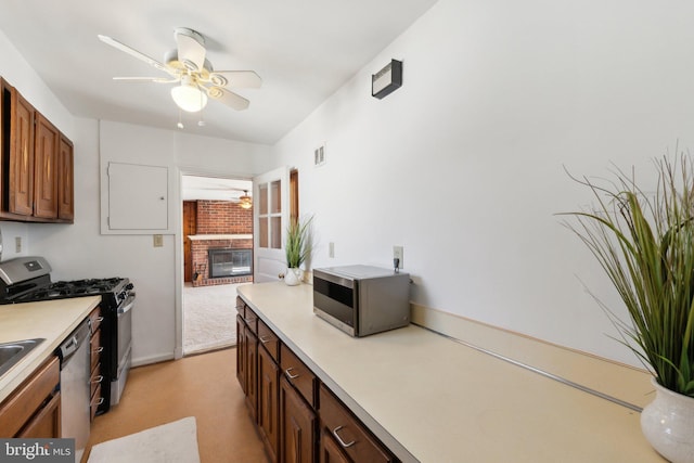 kitchen with visible vents, a ceiling fan, appliances with stainless steel finishes, light countertops, and a fireplace