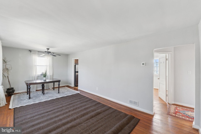 interior space with baseboards, visible vents, ceiling fan, and wood finished floors