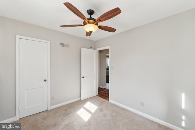 unfurnished bedroom with a ceiling fan, visible vents, light carpet, and baseboards