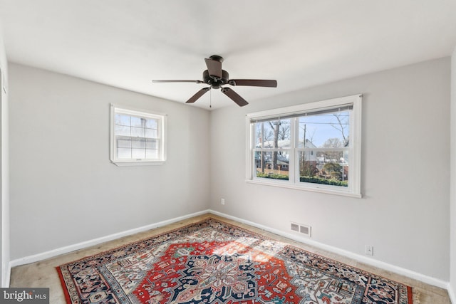 carpeted spare room with ceiling fan, visible vents, and baseboards