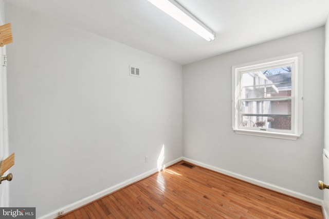 unfurnished room featuring baseboards, visible vents, and hardwood / wood-style floors