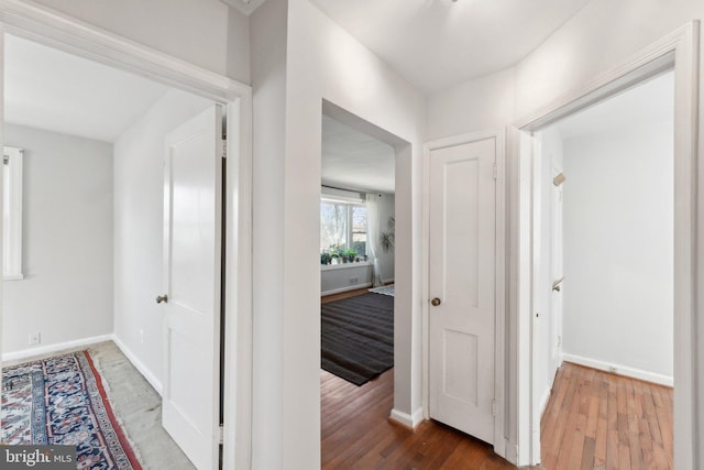 hallway featuring wood finished floors and baseboards