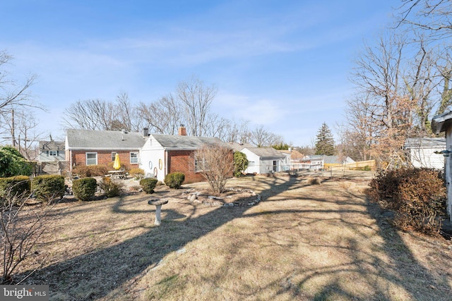 view of front of property featuring brick siding, fence, and a chimney