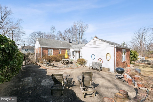 rear view of property with brick siding, a gate, a patio area, fence, and a fire pit