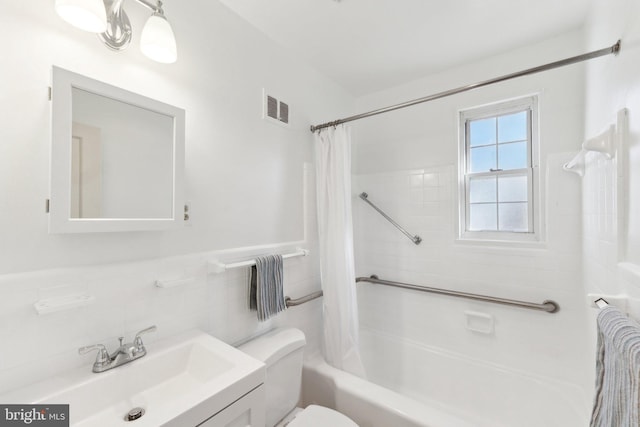 bathroom featuring toilet, vanity, visible vents, tile walls, and shower / bath combo