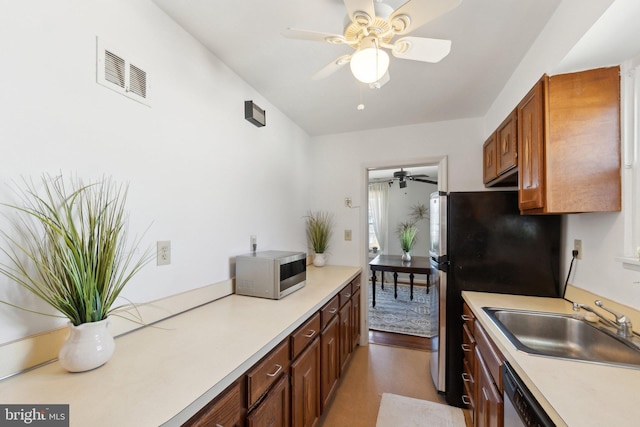 kitchen with light countertops, visible vents, appliances with stainless steel finishes, brown cabinetry, and a sink