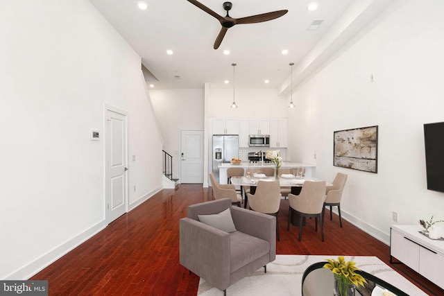 living room with stairs, a high ceiling, dark wood-type flooring, and recessed lighting