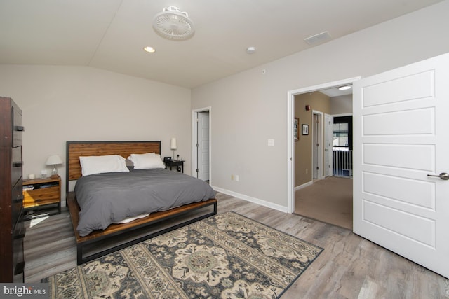 bedroom with visible vents, baseboards, lofted ceiling, and wood finished floors