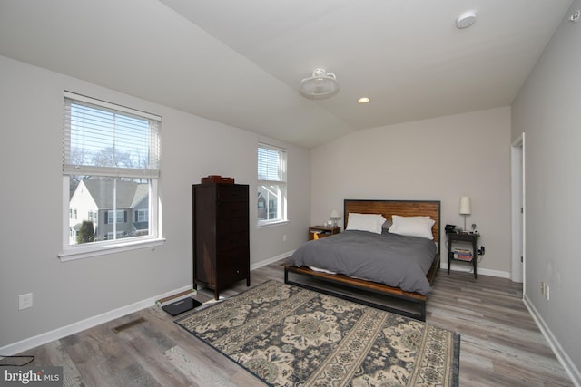 bedroom featuring vaulted ceiling, light wood-style flooring, baseboards, and visible vents