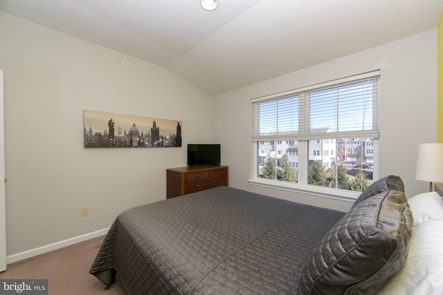 carpeted bedroom with lofted ceiling and baseboards