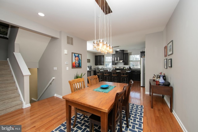 dining room featuring visible vents, baseboards, recessed lighting, stairs, and light wood-style floors