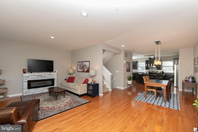 living room featuring a glass covered fireplace, stairway, recessed lighting, and light wood-style flooring