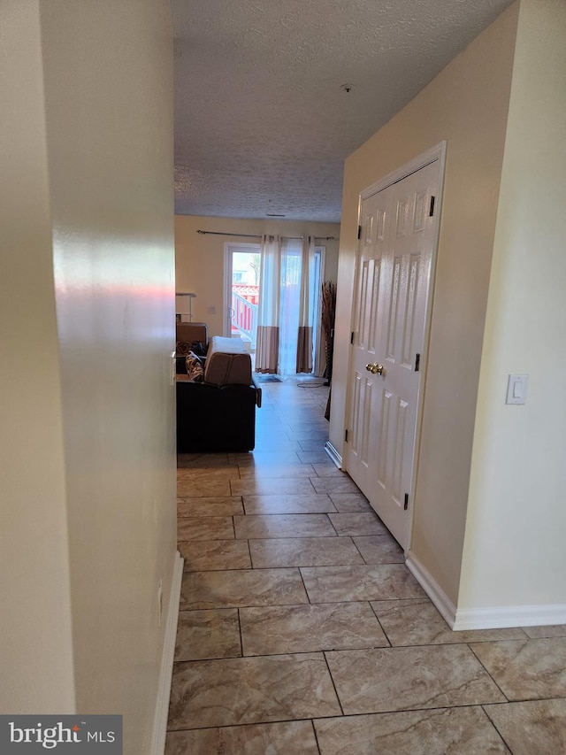 hallway featuring baseboards and a textured ceiling